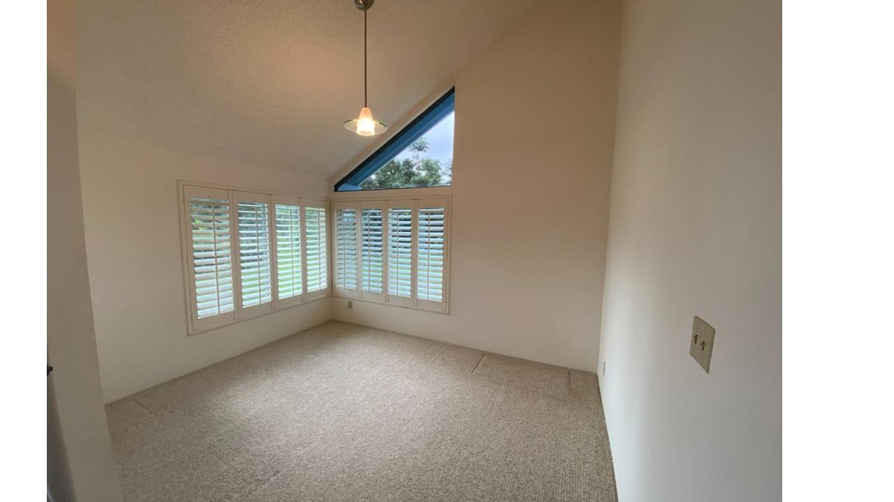 A room with a window covered by white blinds and a light hanging from the ceiling.